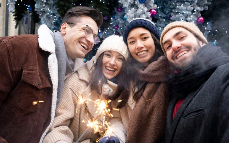 Families enjoying Alton Towers Winter Breaks with festive lights in the background.